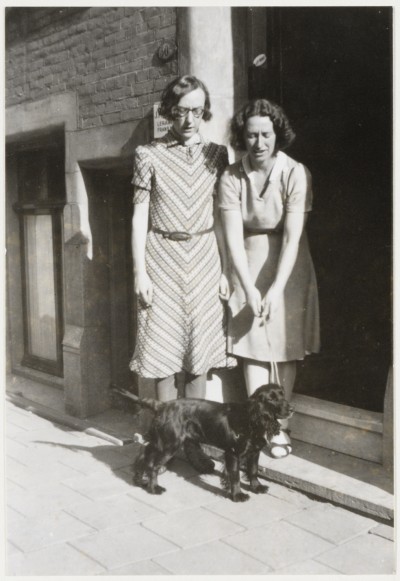 Anna Blaman en Alie Bosch met hondje op de stoep van het huis in de de Vliegerstraat 50a in Rotterdam